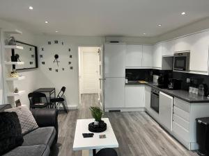 a living room with a couch and a kitchen at Chic & Modern Flat: Perfect for Exploring Kent! in Kent