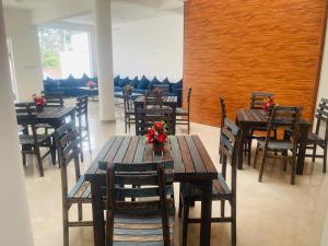 ein Restaurant mit Holztischen und Stühlen mit Blumen darauf in der Unterkunft Lucky Transit Hotel in Katunayaka