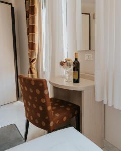Hotel Flora في ستريزا: غرفة بها كرسي وزجاجة من النبيذ