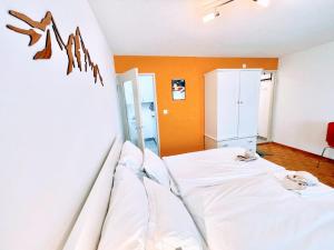 a bedroom with a white bed and an orange wall at Studio Wolli - Stylish & Central - steps to Matterhorn gondola in Zermatt