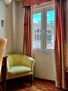 a chair and a window with a view of a building at Carlos V Malaga in Málaga