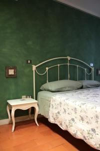 a bedroom with a green wall with a bed and a table at Villa Cardinala - Ravenna in Gambellaro