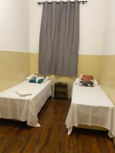 2 Betten in einem Zimmer mit Fenster in der Unterkunft Hotel Central in Araçatuba