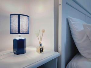 a blue lamp on a white table next to a bed at Modern 2/3 huge bedrooms Heathrow & Central London in Feltham