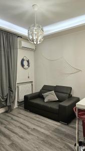 um sofá preto numa sala de estar com um lustre em Casa Mavira House em Rimini