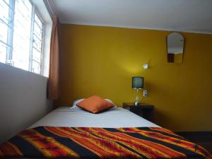 um quarto com uma cama e uma parede amarela em Sumaq Wasi Barranco II em Lima