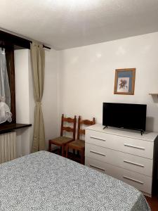 - une chambre avec un lit et une télévision sur une commode dans l'établissement Appartamento Bardonecchia, à Bardonnèche