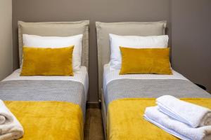 2 bedden met gele en witte kussens in een kamer bij Koukounaraki Apartment 1 in Skiathos-stad