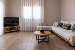 a living room with a white couch and a tv at Koukounaraki Apartment 1 in Skiathos