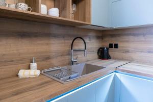 a kitchen with a stainless steel sink and wooden cabinets at Koukounaraki Apartment 1 in Skiathos