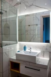a white bathroom with a sink and a mirror at Koukounaraki Apartment 1 in Skiathos