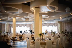 un salón de banquetes con mesas y sillas blancas en Black Tulip Hotel, en Dej