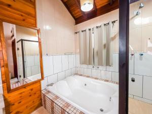 bagno con vasca, doccia e specchio di Chalés Galinha Da Roça a Monte Verde Altre 41 foto