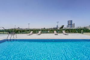 a large swimming pool with chairs on a building at 1 BR Apt, Miracle Garden with RoofTop Pool, King Bed, Gym,100mbps in Dubai