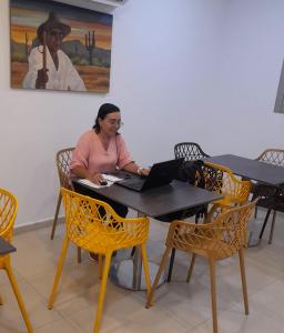 a woman sitting at a table with a laptop at ANAJIRAWAA HOTEL in Ríohacha