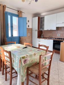 a kitchen with a table with chairs and a kitchen with blue cabinets at 2 bedrooms apartement at Lotzorai 800 m away from the beach with furnished balcony in Lotzorai