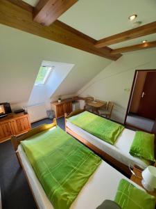 2 łóżka w pokoju na poddaszu z zieloną pościelą w obiekcie Penzion V Podzámčí w mieście Moravská Třebová