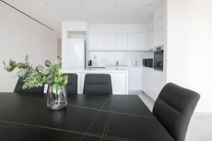 eine weiße Küche mit einem Tisch und einer Vase aus Blumen in der Unterkunft Phaedrus Living Luxury Seaview Coral Bay Villa in Peyia