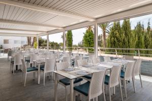 un restaurante con mesas blancas y sillas en una terraza en Apartamentos Vistasol, en Magaluf