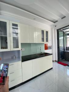 a person taking a picture of a white kitchen at Mimi Homestay in Liên Trì (3)