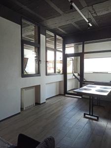 une pièce vide avec une table et quelques fenêtres dans l'établissement Albergue HR, à Sarria