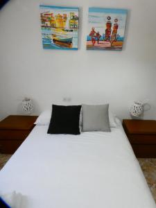 1 dormitorio con 1 cama blanca y 2 cuadros en la pared en Apartamento Tiebas, Cambrils, en Cambrils