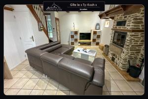 sala de estar con sofá de cuero y chimenea en Aux portes de la baie - Vieux-Viel, en Vieux-Viel