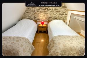 two beds in a small room with a brick wall at Aux portes de la baie - Vieux-Viel in Vieux-Viel