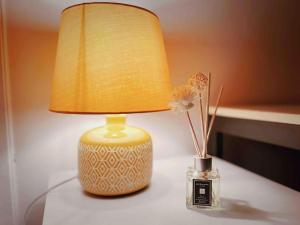 a lamp on a table with a vase with a flower at Modern 2/3 huge bedrooms Heathrow & Central London in Feltham