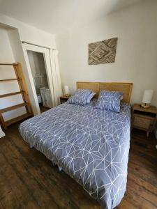 a bedroom with a bed with a blue and white comforter at La tour de guet Maison atypique in Castellane