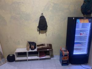 a black backpack hanging on a wall next to a refrigerator at Aqilun Coffe home in Seturan