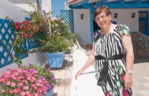 a woman in a dress standing in front of flowers at Filio rooms in Kythira