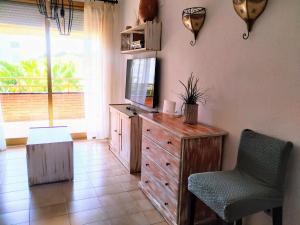 ein Wohnzimmer mit einer Kommode, einem Fernseher und einem Stuhl in der Unterkunft Optimist in Cambrils