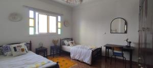 Cette chambre comprend deux lits, un bureau et un miroir. dans l'établissement Free birds hostel, à Tamraght Ouzdar