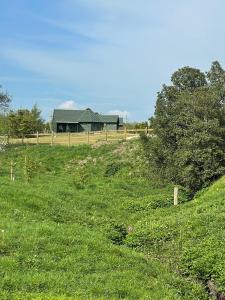 a grassy field with a house in the background at Holly Tree Glamping Cabins in Wigglesworth