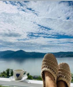 eine Person mit ihren Füßen auf einem Felsvorsprung mit einer Tasse Kaffee in der Unterkunft Dream Tricule in Sviniţa