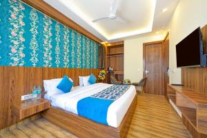 Wood Rose Hotel Near Delhi Airport في نيودلهي: غرفة نوم بسرير وتلفزيون بشاشة مسطحة