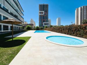 Una piscina con una sombrilla al lado de un edificio. en Apartment Praia Rocha Residence Honey Glow, en Portimão