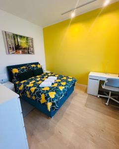 - une chambre avec un lit, un bureau et un mur jaune dans l'établissement Apartment Targowa L10, à Lublin