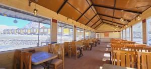 a dining room with tables and chairs and windows at Hotel Spiti Villa Himalayan Brothers in Kaza