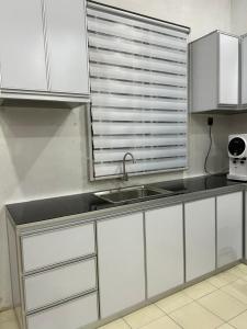 een keuken met witte kasten en een wastafel bij Kembara Homestay Four Room in Alor Setar
