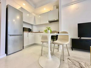 een keuken met een tafel, stoelen en een koelkast bij Double Studio B105 StayInn by Cosmopolis in Creţuleasca