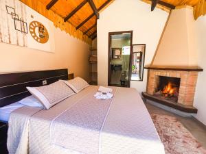 a bedroom with a large bed with a fireplace at Chalés Galinha Da Roça in Monte Verde