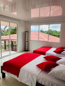 1 dormitorio con 2 camas, almohadas rojas y ventanas en Finca El Descanso, en Villavicencio