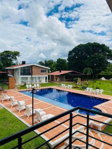 a swimming pool with chairs and a house at Finca El Descanso in Villavicencio