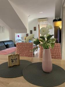 - un vase avec des fleurs sur une table dans le salon dans l'établissement Apartman Dujmović 1, à Otočac