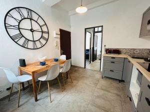 a kitchen with a wooden table and a large clock on the wall at L'Aixalté - T2, Vieille Ville in Aix-en-Provence