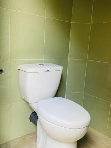 a white toilet in a bathroom with green tiles at Yala Village Eco Tree House in Tissamaharama