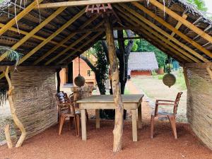 une table et des chaises en bois sous un toit en bois dans l'établissement Yala Village Eco Tree House, à Tissamaharama