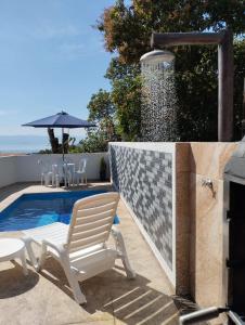 Ein weißer Stuhl steht neben einem Schwimmbecken in der Unterkunft Casa Vista Baepi - Estilo Boho, Mais Streaming a 1,5km da Balsa in Ilhabela
